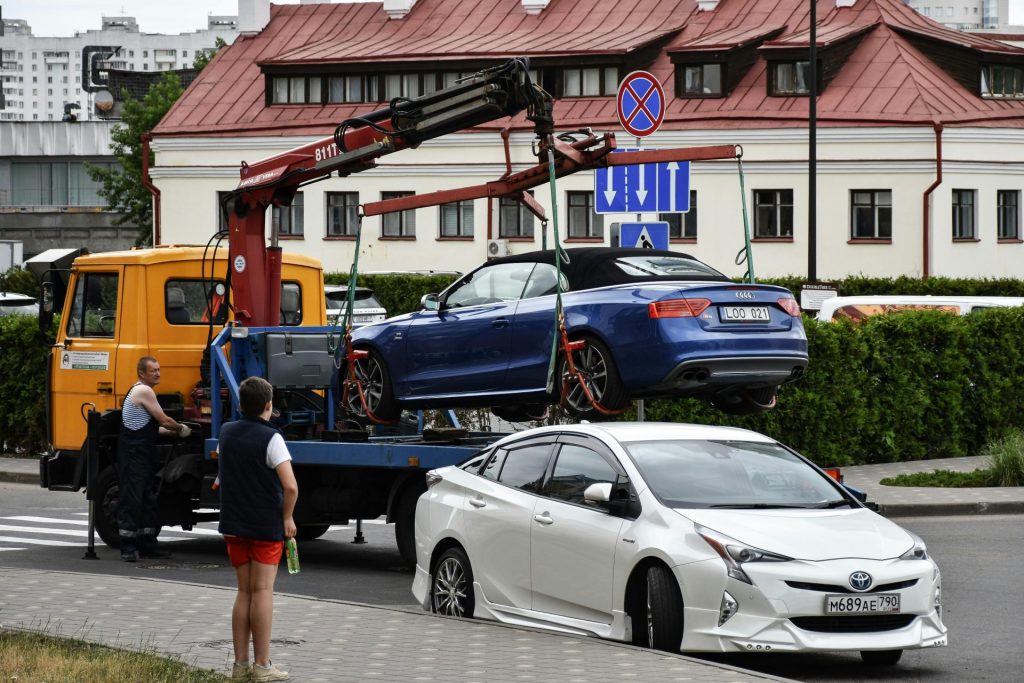 Das Abschleppen eines blauen Audi-Cabriolets in einer belebten Stadtstraße.