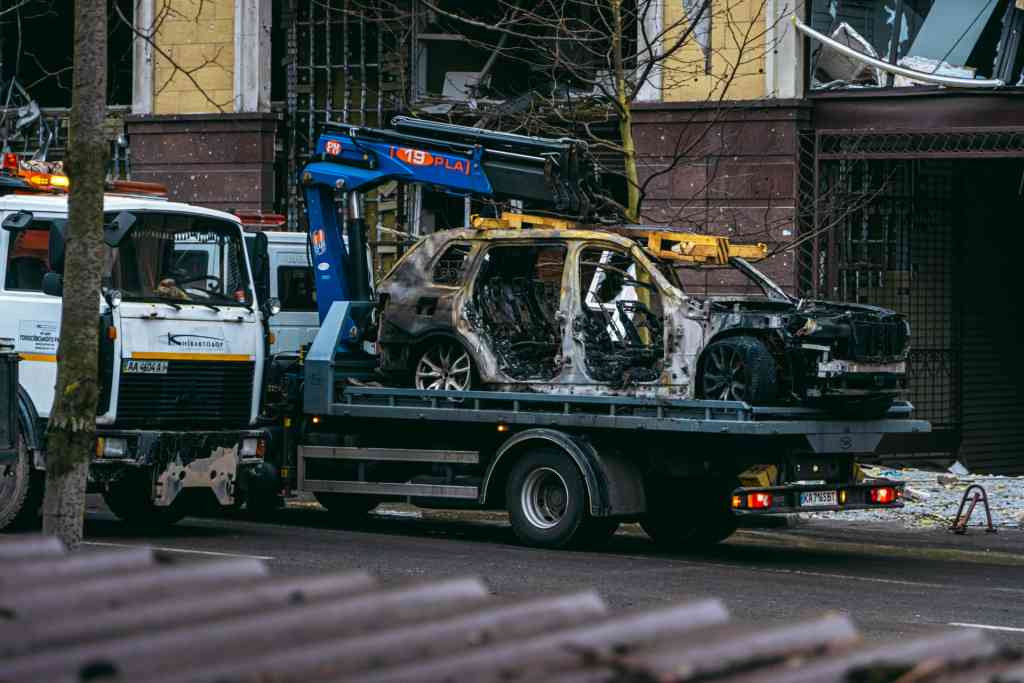 Ein ausgebranntes Auto wird auf einer Straße in Kiew abgeschleppt und verdeutlicht die Folgen des Konflikts.